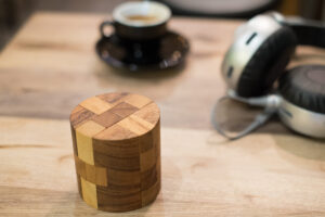 Displays the puzzle Powder Keg as a rustic home decoration next to a cup of coffee and some headphones.