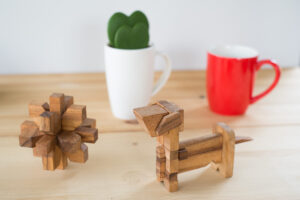 This picture depicts two puzzles set on a table used for decorating homes, The puzzles are Best Friend and Dahlia. They are positioned in front of a coffee mug and a cactus.