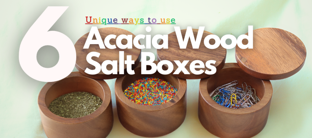 Image depicts three acacaida wood salt boxes containing various items. The leftmost box has oregano, the box in te middle is filled with sprinkles, and the leftmost box has paperclips inside. Over this image the words, "6 Uses for Acacia Wood Salt Boxes" are imposed.