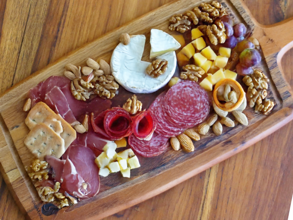 This image depicts more traditional charcuterie board ideas, containing various meats, cheeses and crackers, as well as grapes and nuts.